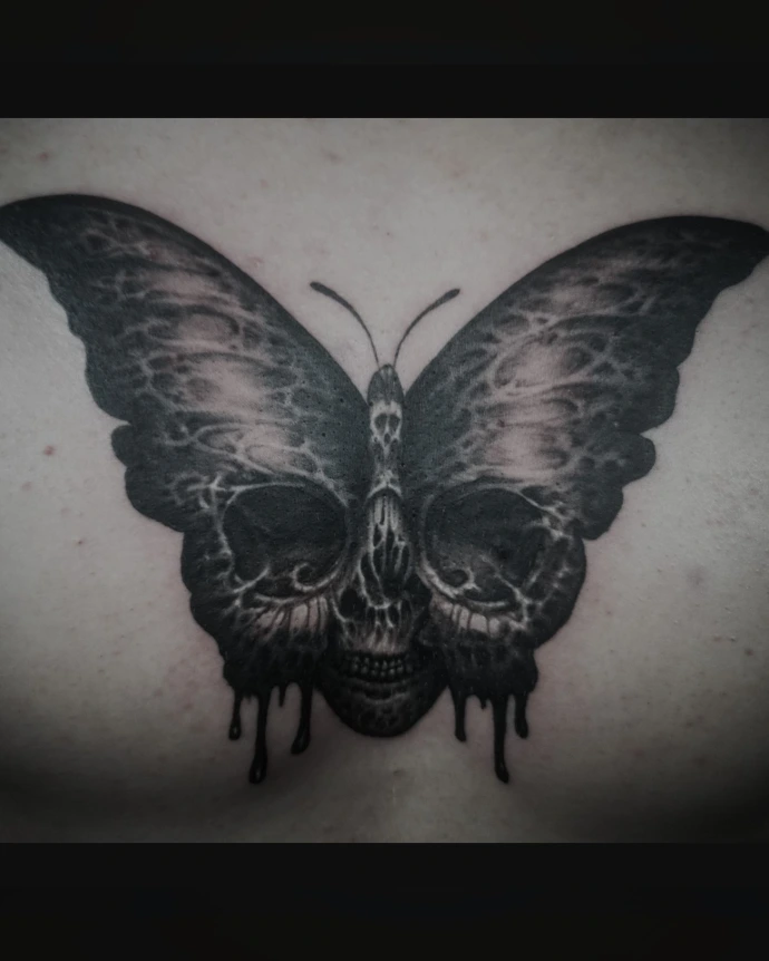 "Dark surrealism butterfly tattoo with hidden skull optical illusion and gothic dripping details.