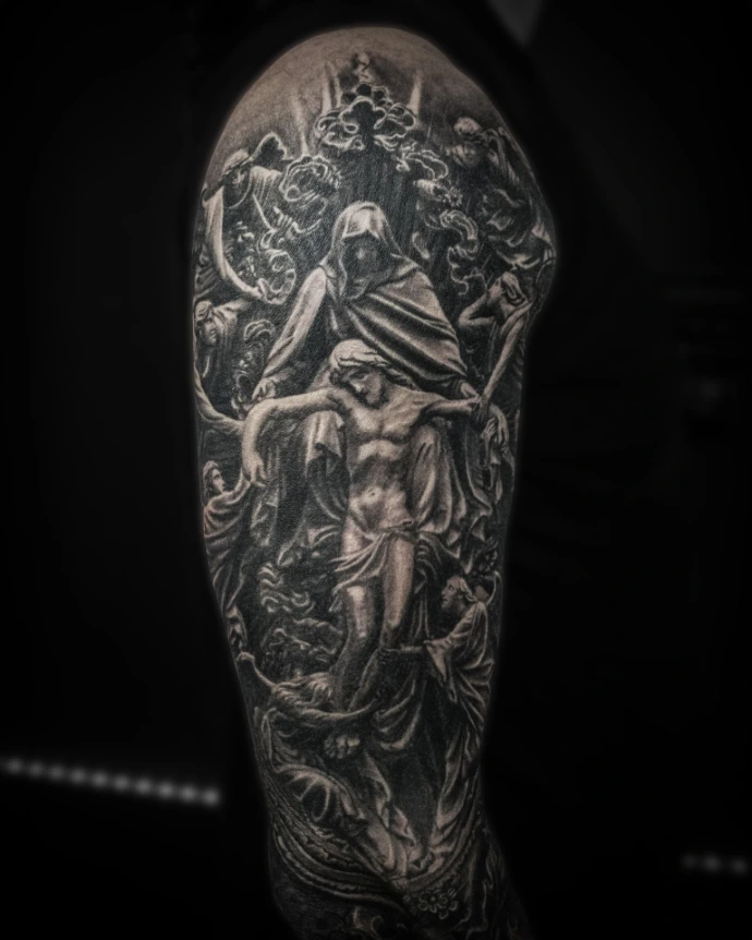 Black and grey religious sleeve detail showing a stone-texture crucifixion of Jesus with angels in the background.