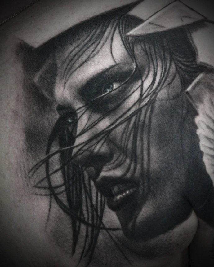 Hyper-realistic female portrait tattoo on the shoulder showing advanced hair texture and layering techniques over the face.